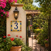 Talavera tile plaque number three with Mexican floral border installed beside a garden gate with lush greenery and stucco accents