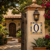 Talavera tile plaque number zero with Mexican floral border displayed beside a traditional hacienda entryway with rustic architectural details