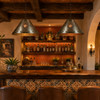 Two rosette punched tin cone pendants with jewels above a rustic hacienda home bar