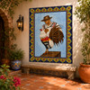 El gallo talavera tile mural in a courtyard with terracotta paving, arches, and leafy greenery.