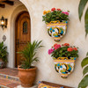 Pair of talavera scroll wall sconces with plants beside a rustic hacienda entryway