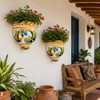 Two Mexican talavera scroll wall sconces with plants decorating a warm covered porch