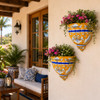 Two blue and orange talavera wall sconces with plants decorating a covered porch