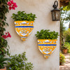 Blue and orange talavera wall sconces with flowers displayed on a sunny garden wall
