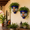 Two lattice-design talavera wall sconces with plants decorating a covered porch