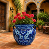 Blue and white Talavera pot filled with lush plants in a colorful Mexican courtyard