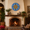 Colorful floral decorative talavera plate with blue scrollwork design displayed above a rustic hacienda fireplace mantel