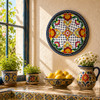 Floral lattice decorative talavera plate with black border design displayed near a sunny window illuminated by natural daylight