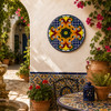 Orange scroll decorative talavera plate with cobalt geometric pattern mounted in a Mediterranean courtyard with natural light