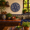 Blue bird decorative talavera plate with floral vine design displayed on a rustic Mexican kitchen wall with colorful artisan accents