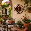 Blue medallion decorative talavera plate with yellow lattice design mounted in a bright Mediterranean courtyard with garden views