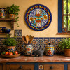 Cobalt blue decorative talavera plate with orange floral medallion displayed on a colorful Mexican kitchen wall with traditional handcrafted decor