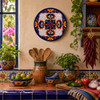 Cobalt rim decorative talavera plate with red floral lattice design displayed on a colorful Mexican kitchen wall above handcrafted cabinetry