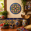 Blue medallion decorative talavera plate with green scrollwork design displayed on a colorful wall in a traditional Mexican kitchen setting