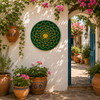Bottle green decorative talavera plate with yellow mandala flower decorating a sunlit Mediterranean courtyard wall