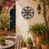 Red floral decorative talavera plate with blue geometric pattern enhancing a Mediterranean courtyard with natural light and greenery