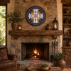 Cobalt blue floral decorative talavera plate with geometric border displayed above a rustic fireplace with natural stone textures