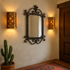 Jewel-studded bronze tin wall sconce light set illuminating a Spanish revivial style house entry