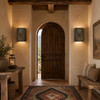 Two punched metal wall sconces with spiral sunburst cutouts in a warm rustic entryway