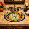 Round talavera bathroom sink floral starburst design in Spanish bathroom with warm tiles and wood vanity