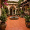 Mexican washed terra cotta talavera tiles for walls and backsplashes decorating a Spanish courtyard with arches, stonework, and greenery