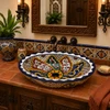 Double sided hand painted oval baroque bathroom sink in Spanish Revival vanity setting