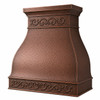 Angled view of hammered copper range hood with scrollwork bands, flared shoulders, and decorative apron