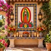 Mexican tile mural wih virgen Guadalupe featured at an outdoor altar with hacienda-style decor.