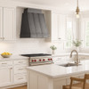 Natural zinc range hood with vintage design featured in a transitional kitchen with white cabinetry