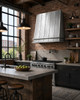 Natural zinc hood in an industrial loft kitchen with brick walls, black steel windows, concrete and reclaimed wood