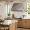 Minimalist hammered zinc range hood in a modern farmhouse kitchen with white oak cabinets and handmade tile