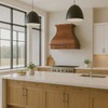 Copper range hood with apron scroll in modern kitchen, smooth canopy with decorative band above range and clean cabinetry
