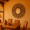 Round wrought iron mirror with ornate scrollwork in Southwestern dining room with adobe textures, leather chairs and warm desert tones