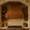 Copper kitchen vent with decorative rings displayed in a Tuscan style kitchen with wood cabinetry