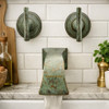 Brass wall mount faucet with patina finish in a bathroom with a marble counter and white subway tile backsplash