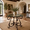 Forged iron table legs - decorative scroll in a Mediterranean interior with a clear glass top