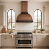 Dome bell copper hood in dull antique light coffee in Mediterranean kitchen with limestone counters