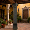 Rustic cantera stone column with carved capital in a Mexican colonial courtyard with clay planters