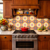 Talavera relief tile floral cartouche design installed as kitchen backsplash behind range, raised ceramic border adding depth and texture