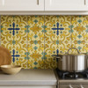 Mexican relief tile golden cross arabesque design displayed on a bright kitchen backsplash with 4x4 tiles
