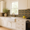 Ornate floral scroll relief tile installed as a decorative backsplash in a bright Spanish kitchen.