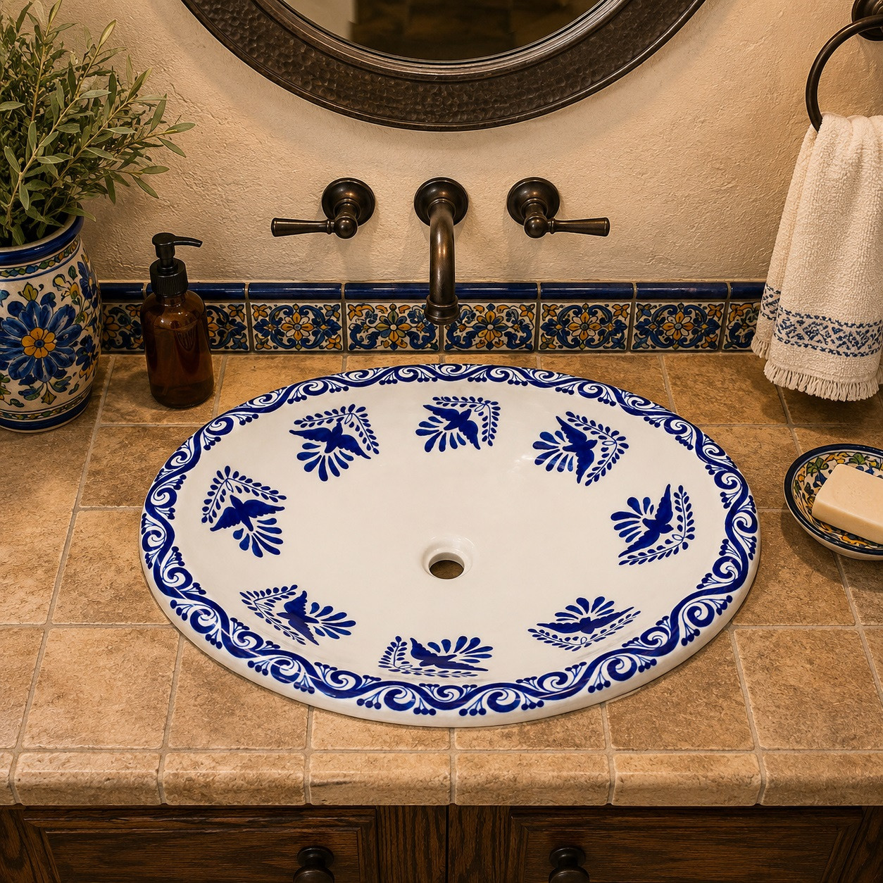 Oval mexican bathroom sink cobalt bird design installed in Spanish Revival bathroom with wrought iron mirror and tile wall