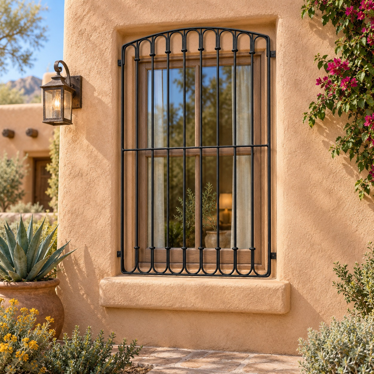 Spanish Revival iron window guards for arched windows on a sunlit adobe house facade