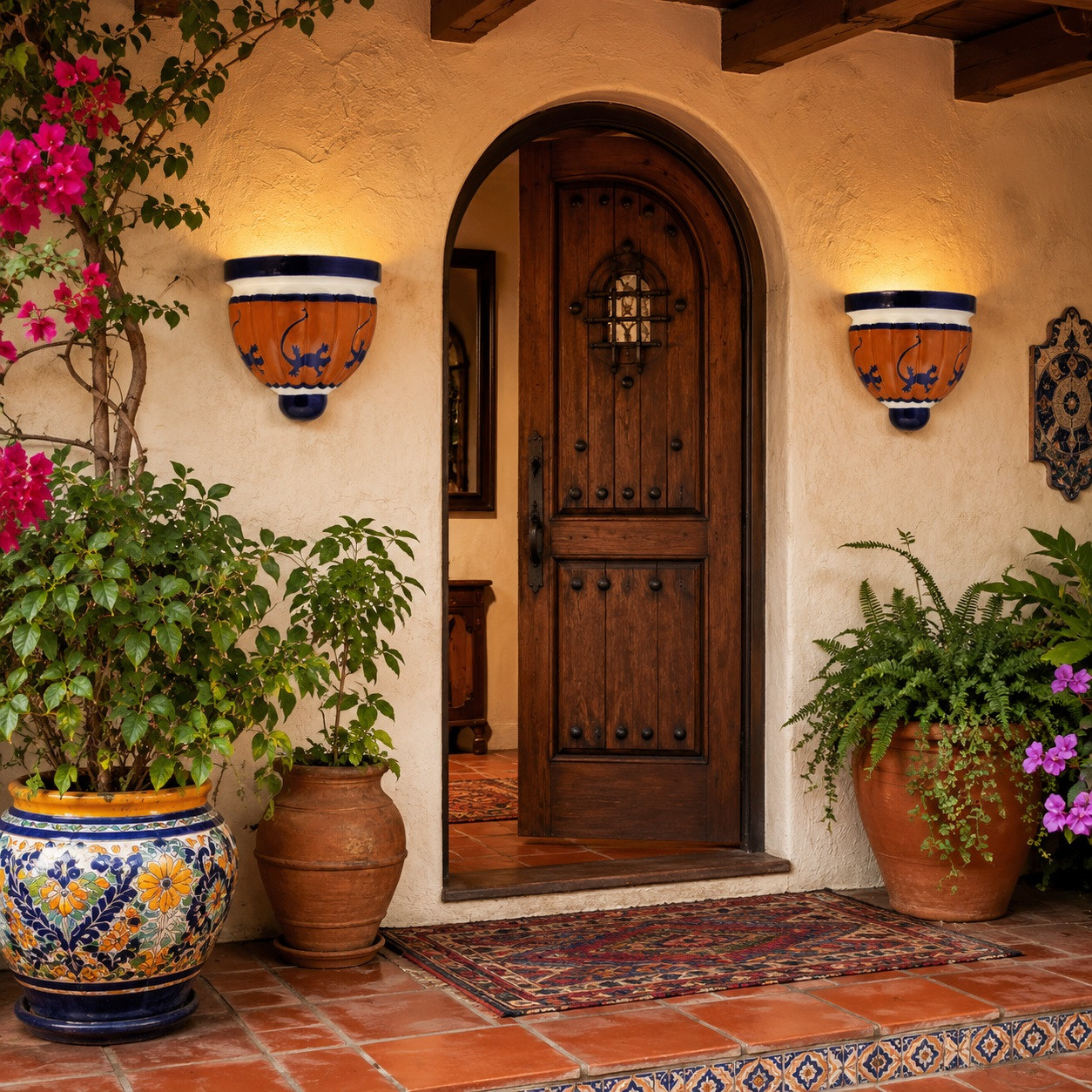 Pair of talavera lizard wall sconces with plants beside a rustic hacienda entryway