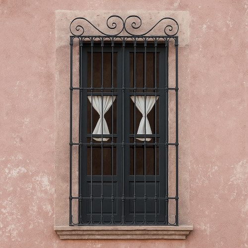 Black iron window guard with scroll top design installed on a Spanish revivial style archicture