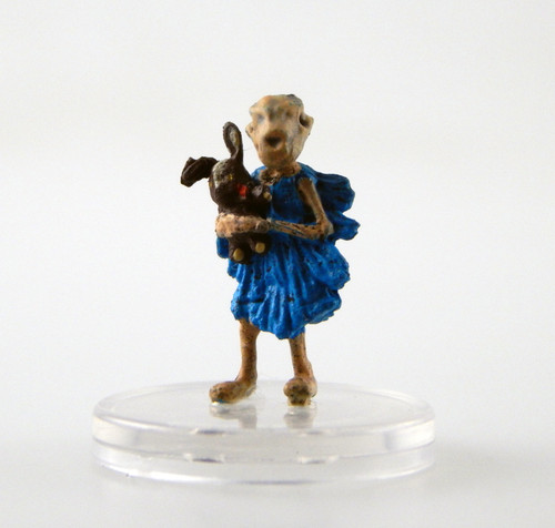 This thing resembles a gray, emaciated child, with cobwebs and dust for clothes and a fox skull for a head. It has a loose, blue frock and clutches a tattered, stuffed and well loved rabbit toy. (Front View)