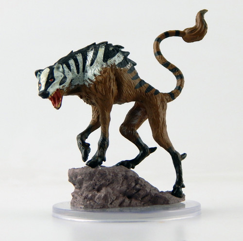 This freakish beast has the head of a badger, the hooves of a stag, and a wide mouth with sharp ridges of bone instead of teeth. It stands screaming atop a small rocky outcrop, its tail lashing wildly. (Side View)