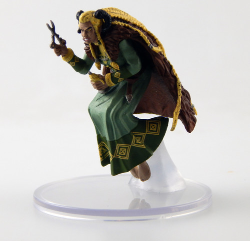 This towering, stern woman wears her long blonde hair in braids. Hovering before you in a subtle, long, green dress and furred cloak, she carries a reel of golden thread and a pair of shears. (Side View)