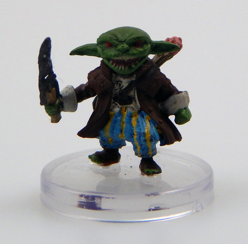 An image of a goblin war chanter bearing a sharp dogslicer. Sharp teeth show in his widely grinning mouth above blue and yellow striped pants and a dapper travelling jacket. On his back rests a bow and quiver of arrows. (Front View)