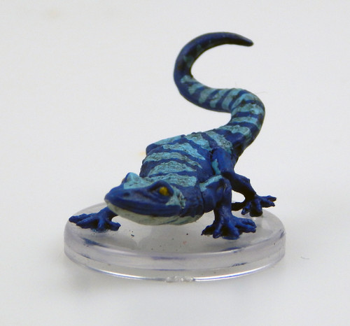 An oversized lizard the size of a horse scans the area, its bulging eyes darting this way and that. Its body is a rich blue with lighter blue mottled stripes running down its head, spine, and tail. (Front View)